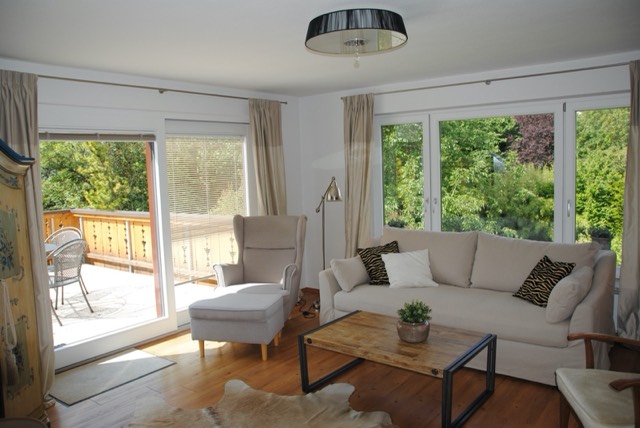 Wohnzimmer mit Couch, Sessel und Zugang zur Dachterrasse